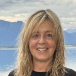 Heike Bohn Sprecher*in des Grünen Ortsverbands Prien, steht vor dem Chiemsee. Blickt freundlich in die Kamera.